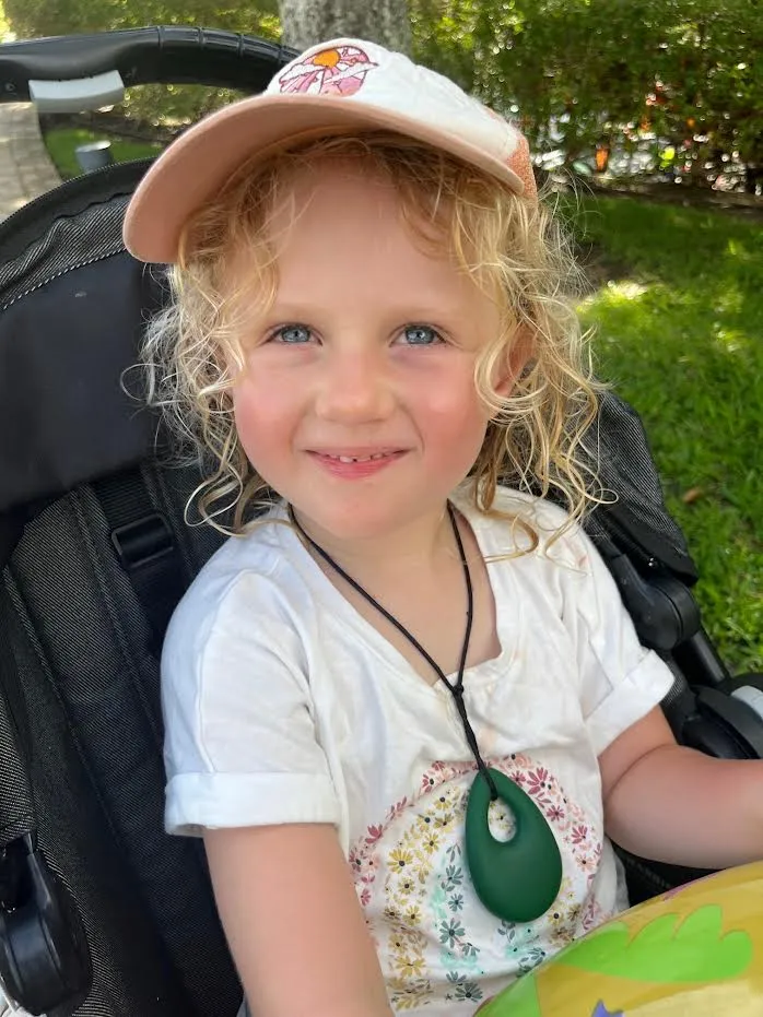 A child living with an STXBP1 disorder, smiling in her wheelchair.