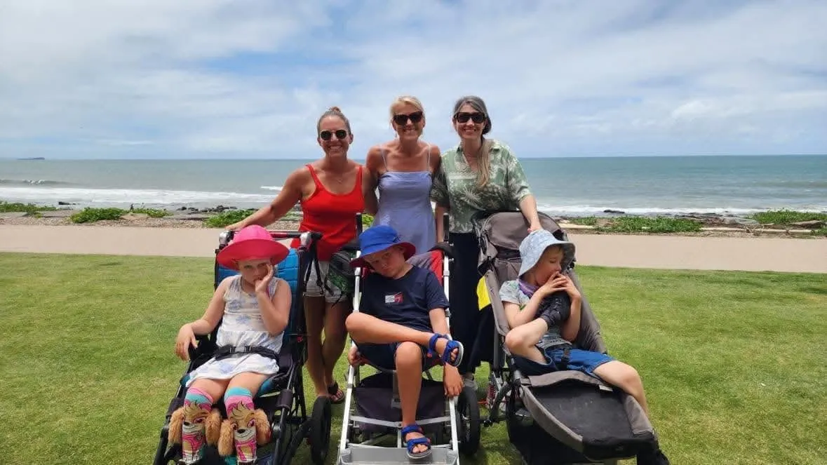 STXBP1 Australia families gathered on the grass by the beach, children in their wheelchairs.