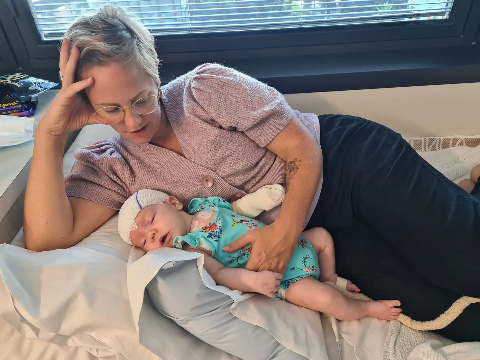 A mum lying beside her baby, who has an STXBP1 disorder, gently watching over her.