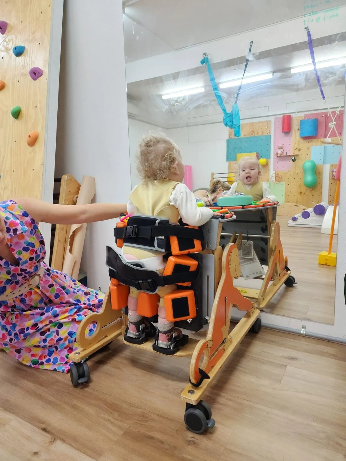 A young girl with an STXBP1 disorder in a supported standing frame at therapy.
